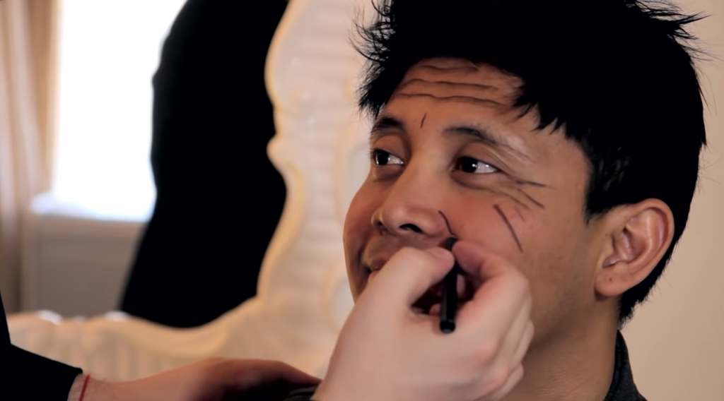 Man applying makeup to create fake wrinkles on face